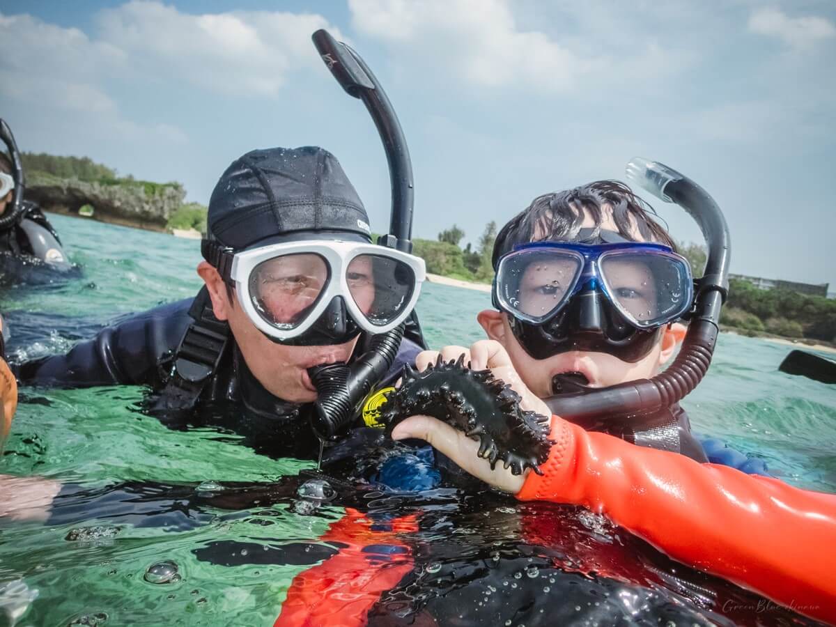 오키나와 패밀리 스노클링 진행 중 강사가 건넨 바다 생물을 관심 있게 보는 할머니와 손주